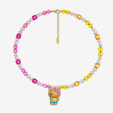 Pink crystals on one side meet yellow and orange crystals on the other, with white crystal pearls throughout. A winking Hello Kitty charm with a pink flower and tropical outfit brings the colors together.