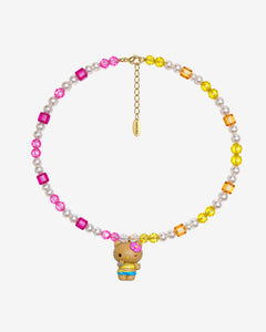 Pink crystals on one side meet yellow and orange crystals on the other, with white crystal pearls throughout. A winking Hello Kitty charm with a pink flower and tropical outfit brings the colors together.